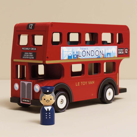 Red wooden double-decker toy London bus with a driver figurine standing in front of it.
