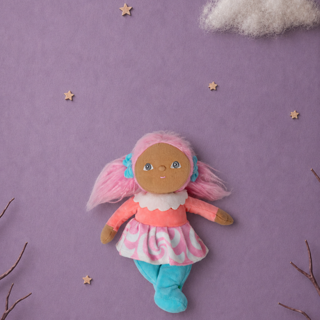 Plush doll with pink pigtails centered on a lavender background with stars and clouds.