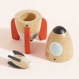 Disassembled wooden space rocket toy set showing the launch base, cone top, and small mini rocket.