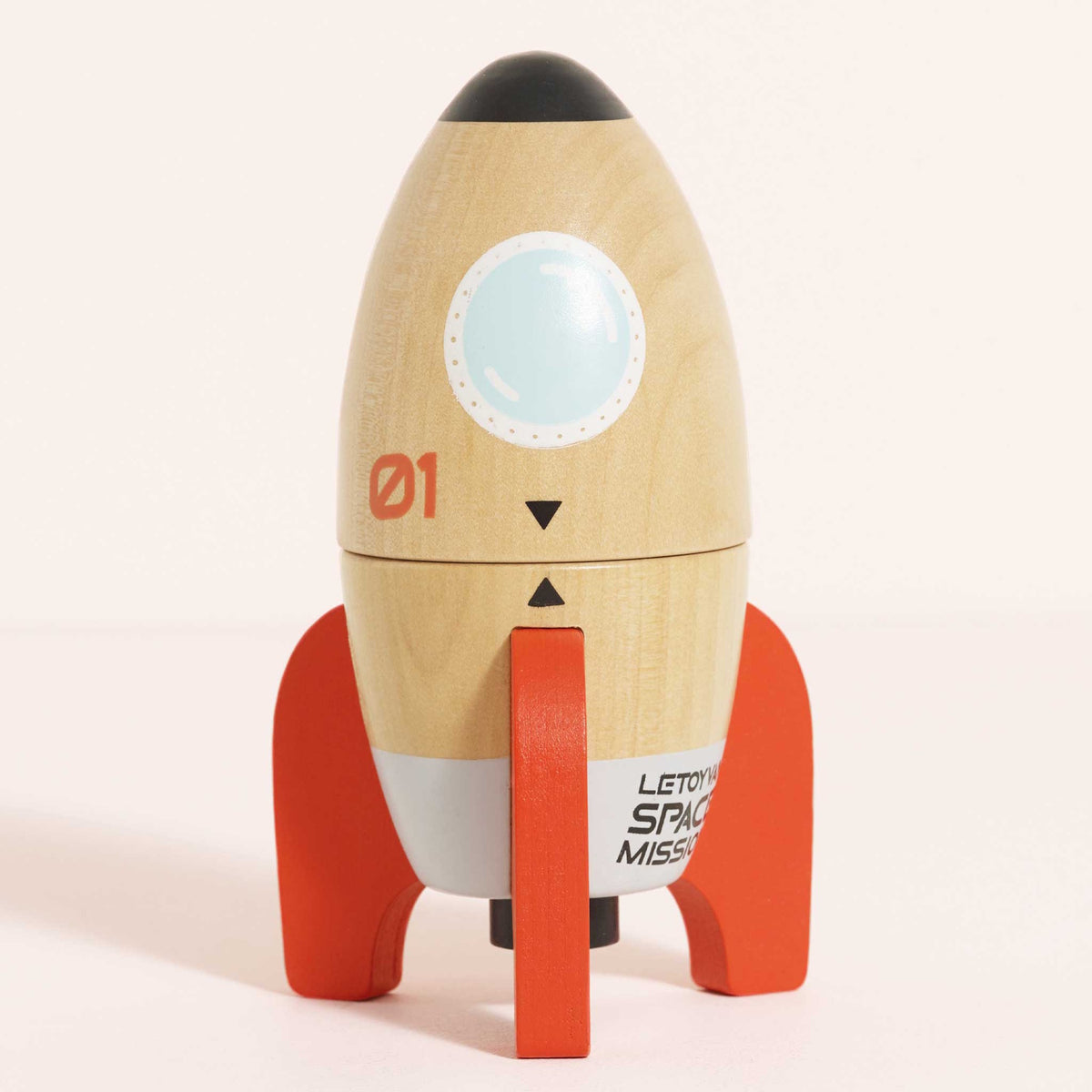 Fully assembled wooden toy space rocket with red fins standing upright against a light background.