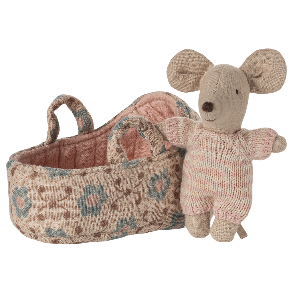Toy mouse in soft pink knit outfit stands beside a fabric basket with floral patterns. The scene evokes warmth and playfulness.
