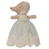 A soft toy with a mouse-like snout and closed eyes, wearing a delicate lace bonnet and a pale blue, lace-trimmed dress, set against a white background.