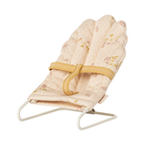 Soft, pink miniature doll chair with floral patterns on a white wire frame, featuring a yellow fabric strap. The design feels delicate and vintage.
