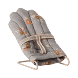 Miniature gray floral baby chair with soft padding and metal frame. It features a harness, scattered orange and brown flowers, and a cozy, vintage feel.