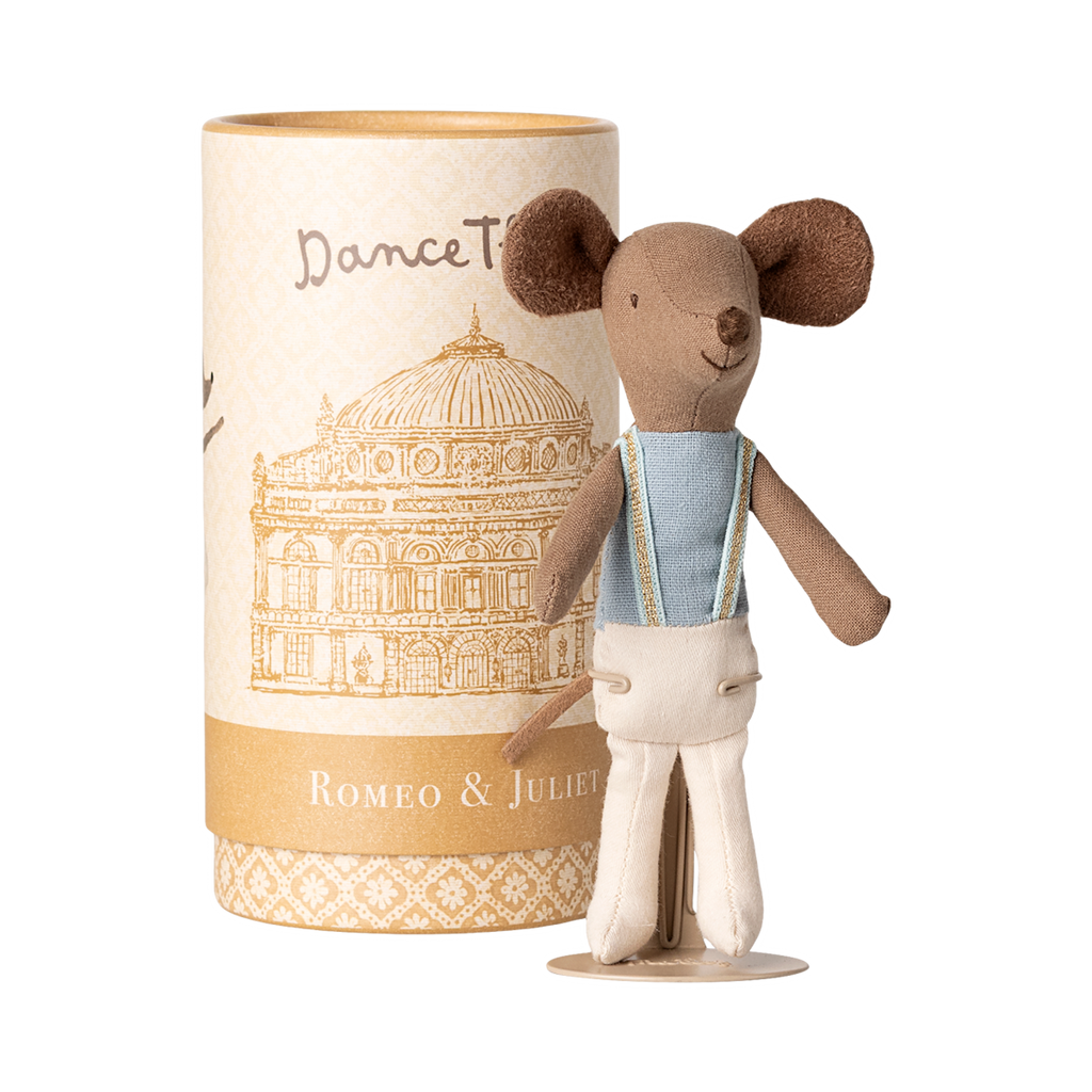 A cute toy mouse in a blue shirt with suspenders stands beside a cylindrical box featuring an illustration of an ornate building, labeled "Romeo & Juliet."