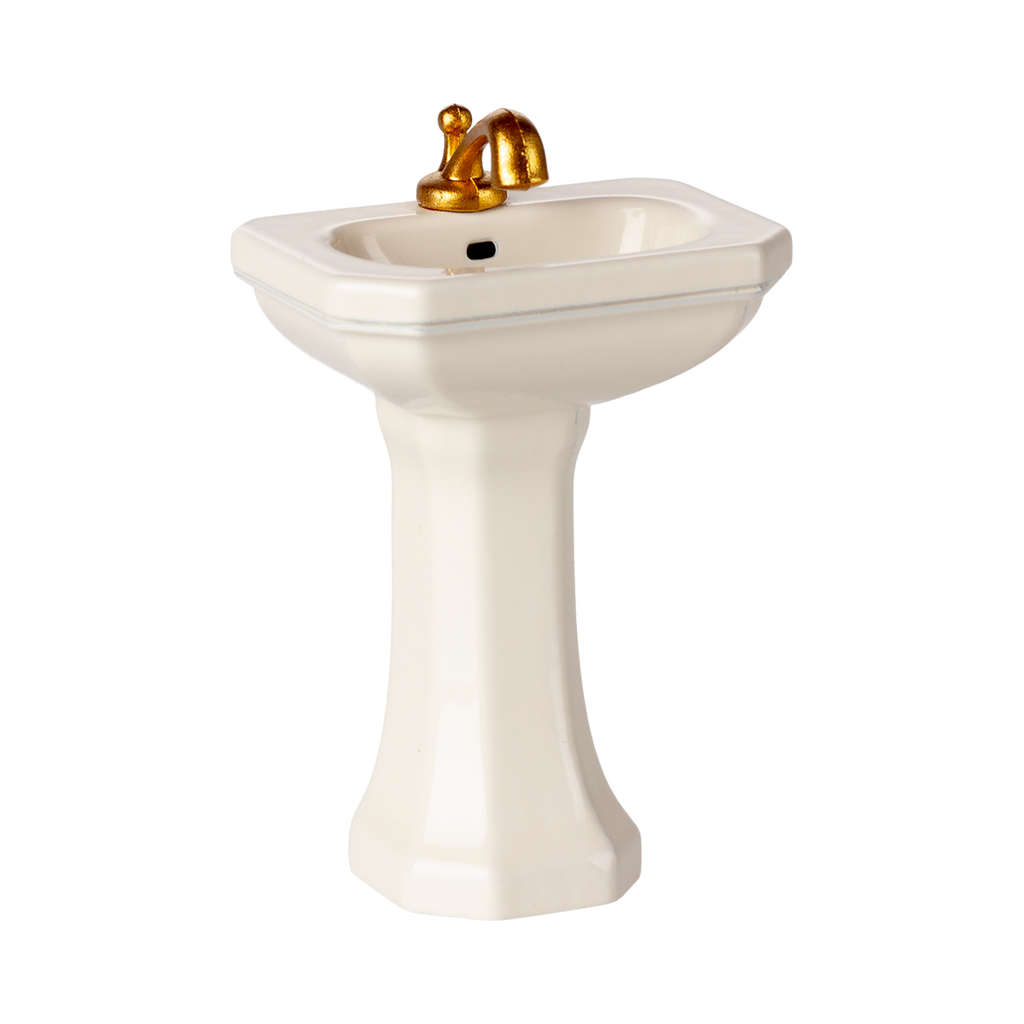 A miniature porcelain pedestal sink with a glossy finish and golden faucet. This elegant bathroom fixture conveys a sense of luxury and vintage charm.