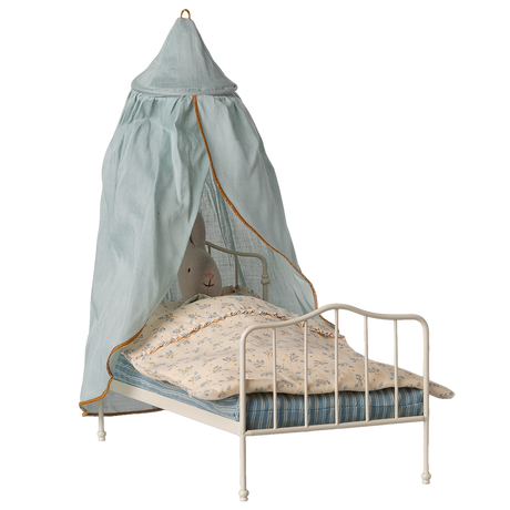 A small white metal bed with a stuffed rabbit under a floral blanket, covered by a light blue canopy with an orange trim, against a white background.