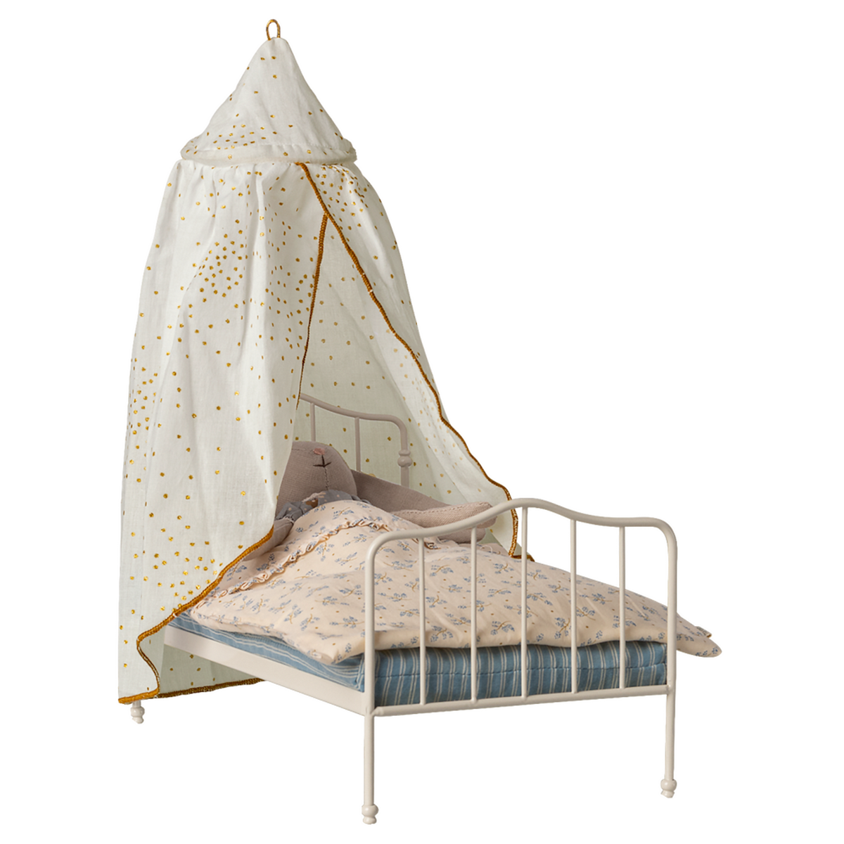 A miniature white metal bed with a blue-striped mattress and floral-patterned bedding. A white canopy with golden spots drapes over, creating a cozy, whimsical feel.