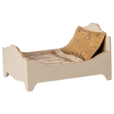 A vintage-style miniature bed with a quilted mattress and a decorative gold pillow, showcasing a charming rustic design in a white background.