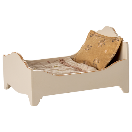 A vintage-style miniature bed with a quilted mattress and a decorative gold pillow, showcasing a charming rustic design in a white background.