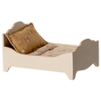 A vintage-style miniature bed with a quilted mattress and a decorative gold pillow, showcasing a charming rustic design in a white background.