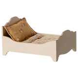 A vintage-style miniature bed with a quilted mattress and a decorative gold pillow, showcasing a charming rustic design in a white background.