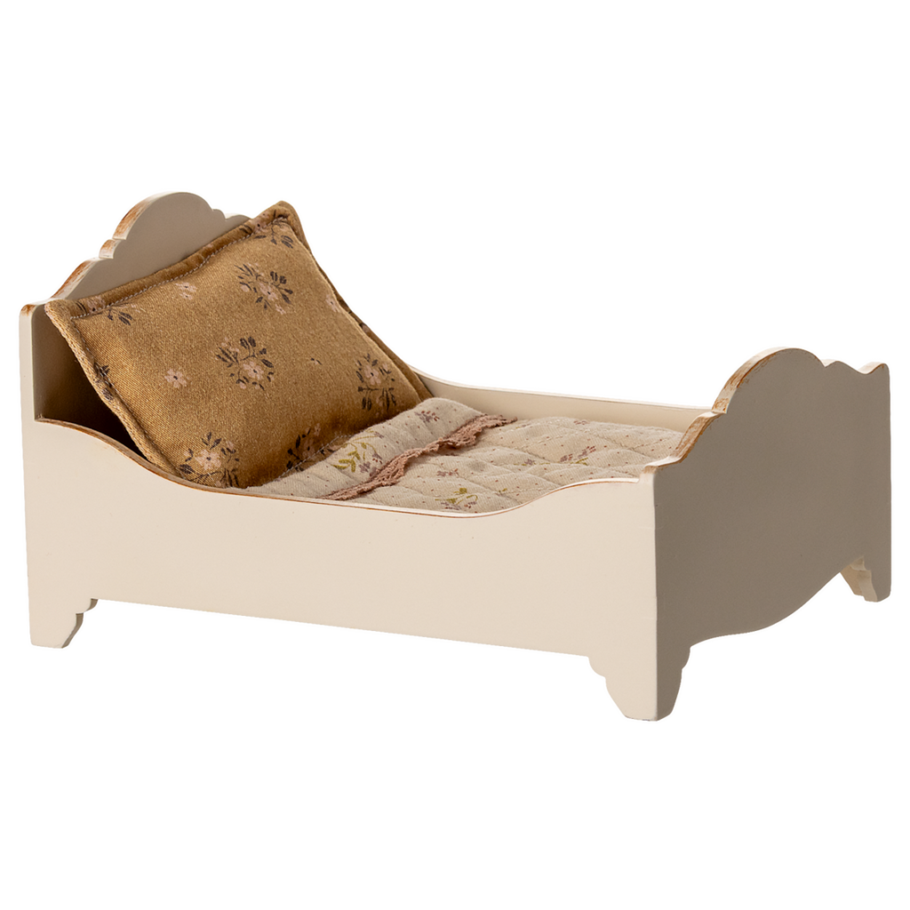 A vintage-style miniature bed with a quilted mattress and a decorative gold pillow, showcasing a charming rustic design in a white background.