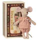 A plush toy mouse in a pink, polka-dotted dress stands against a vintage-style matchbox with a "Mouse Race" design. The toy and box evoke a charming, nostalgic feel.