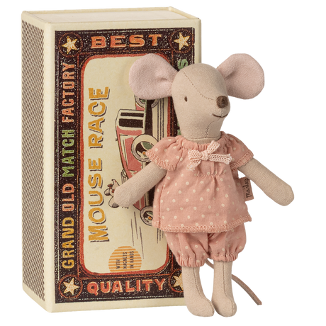 A plush toy mouse in a pink, polka-dotted dress stands against a vintage-style matchbox with a "Mouse Race" design. The toy and box evoke a charming, nostalgic feel.
