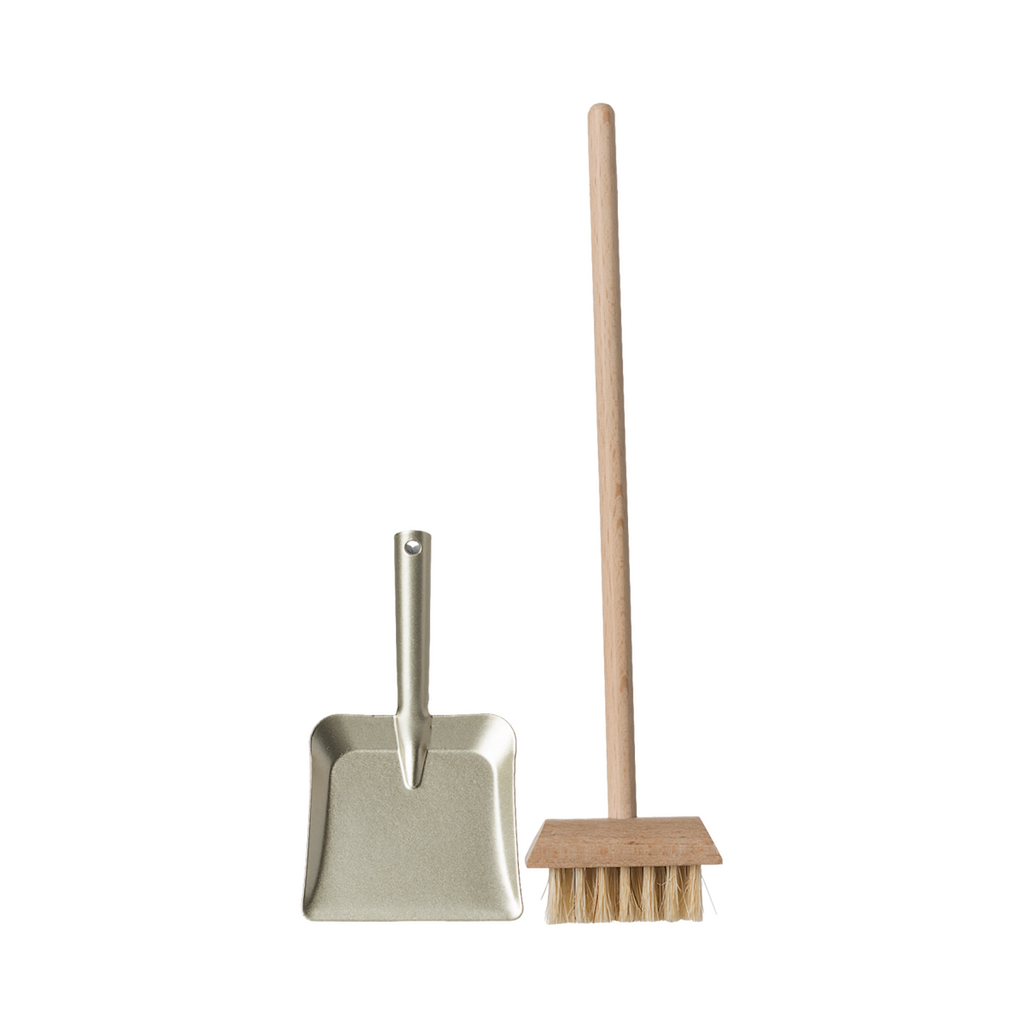 A miniature dustpan with a metal finish and a wooden-handled broom with natural bristles are placed upright on a plain background, evoking simplicity and cleanliness.