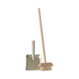 A miniature dustpan with a metal finish and a wooden-handled broom with natural bristles are placed upright on a plain background, evoking simplicity and cleanliness.