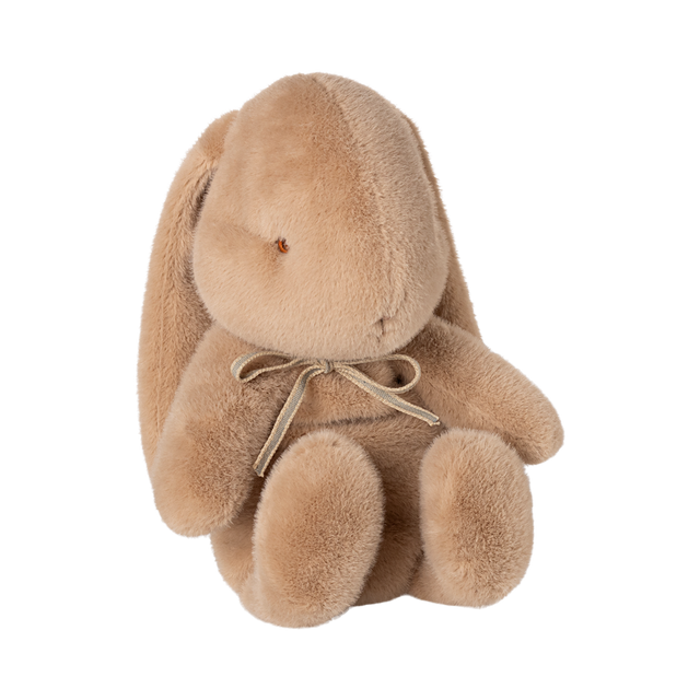 A plush, light brown stuffed bunny with long ears sits upright. It has a simple facial expression and wears a bow, conveying a sense of softness and warmth.