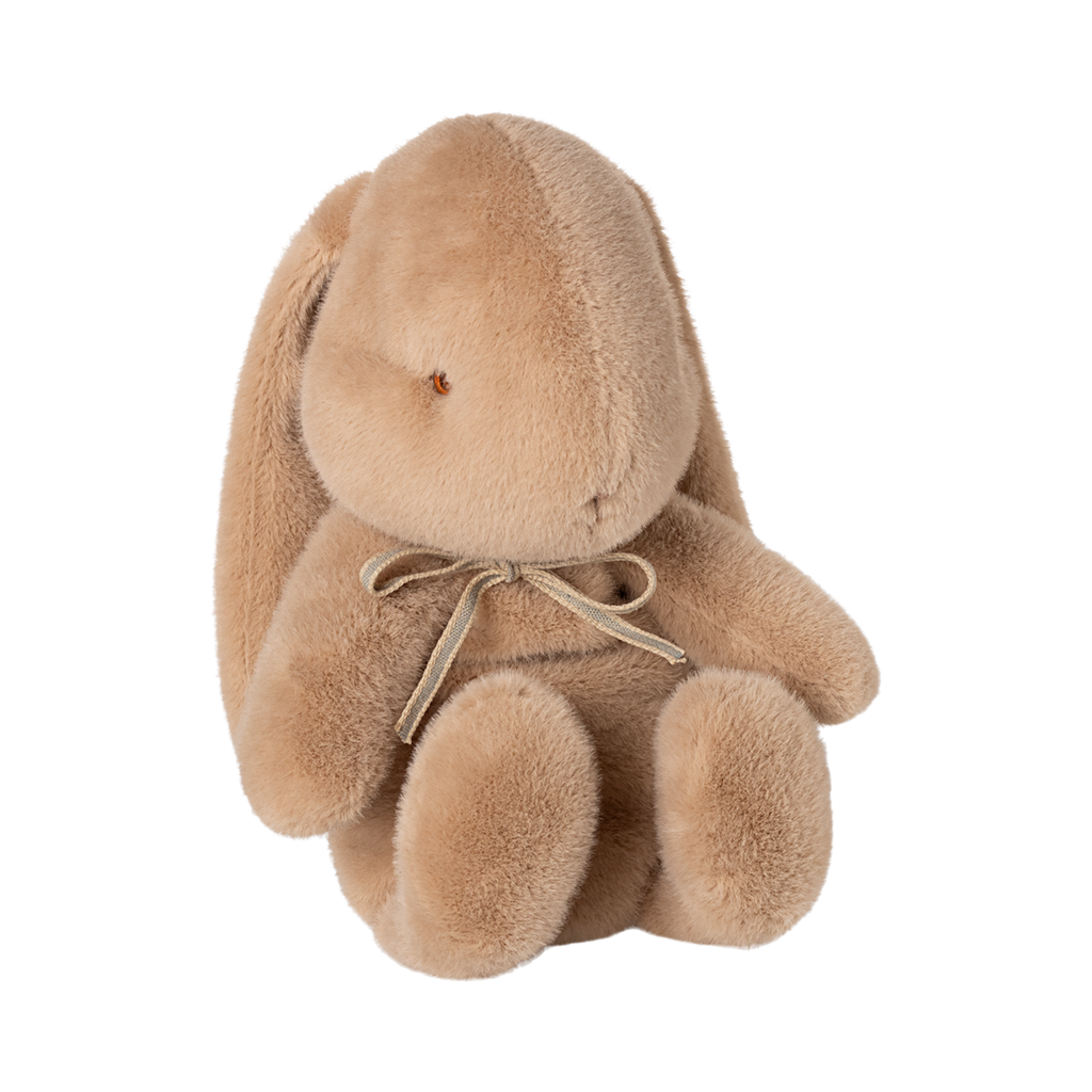 A plush, light brown stuffed bunny with long ears sits upright. It has a simple facial expression and wears a bow, conveying a sense of softness and warmth.
