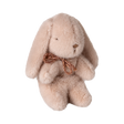 A fluffy, light brown stuffed bunny with droopy ears and a simple embroidered face sits upright. It wears a small, brown bow around its neck.