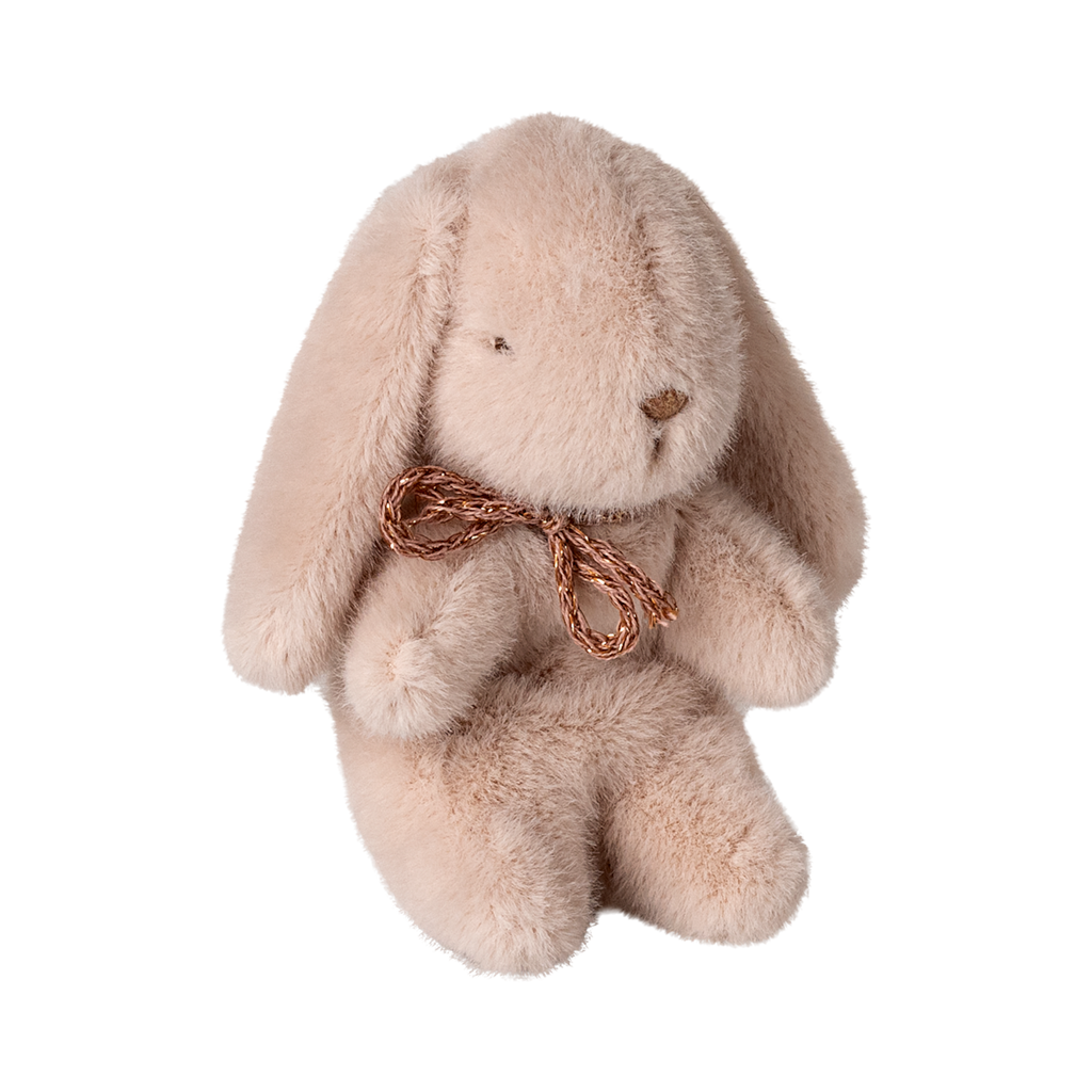 A fluffy, light brown stuffed bunny with droopy ears and a simple embroidered face sits upright. It wears a small, brown bow around its neck.