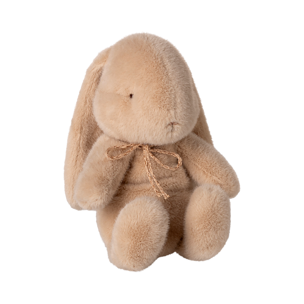 A plush tan bunny with floppy ears and a delicate bow around its neck sits against a plain background, conveying a gentle and cozy vibe.