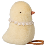 Fluffy yellow chick plush with small orange beak and lace flower collar, on a white background. The chick sits upright, evoking a cute and whimsical tone.