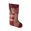 A festive patchwork Christmas stocking in red hues, featuring various patterns and textures, perfect for holiday decorating.