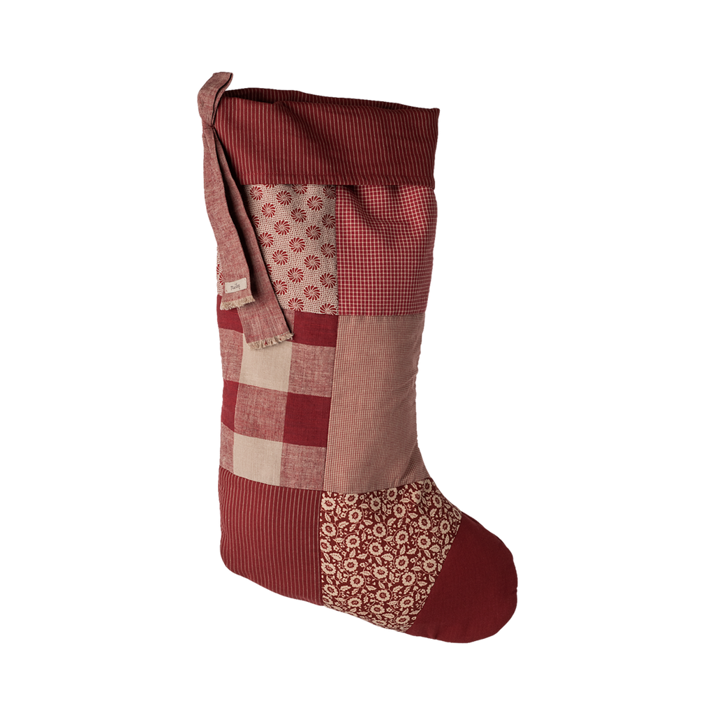 A festive patchwork Christmas stocking in red hues, featuring various patterns and textures, perfect for holiday decorating.