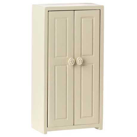 A small cream-colored cupboard with two panelled doors, each featuring a round flower-patterned knob, set against a plain white background.