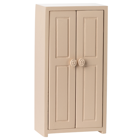 A small, beige, two-door cabinet with simple panel designs and round floral knobs, set against a white background, conveying a minimalist style.