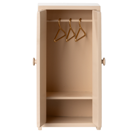 A beige, wooden wardrobe with open doors showing three golden hangers on a rail inside. The design is simple and minimal against a white background.