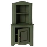 Green wooden corner miniature cabinet with an open lower door. It features two shelves above and a decorative knob. The piece conveys a rustic, vintage charm.