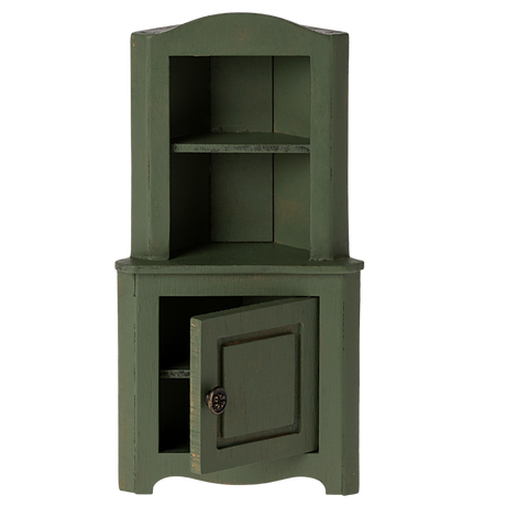 Green wooden corner miniature cabinet with an open lower door. It features two shelves above and a decorative knob. The piece conveys a rustic, vintage charm.