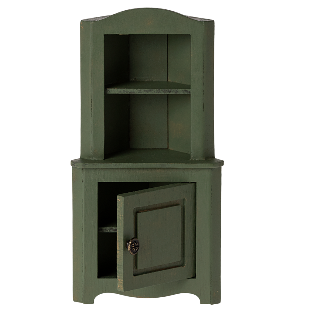 Green wooden corner miniature cabinet with an open lower door. It features two shelves above and a decorative knob. The piece conveys a rustic, vintage charm.