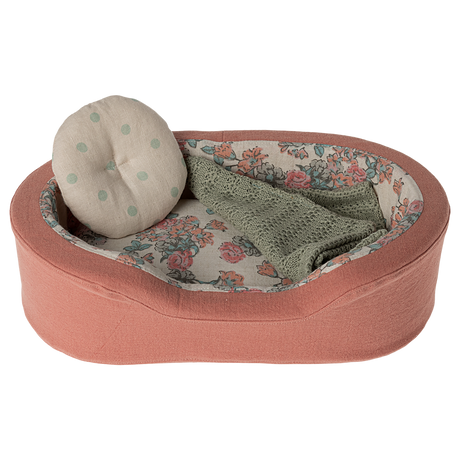 The image shows a soft toy dogs bed in coral, with a pillow and blanket on a white background.
