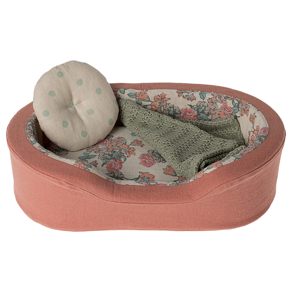 The image shows a soft toy dogs bed in coral, with a pillow and blanket on a white background.