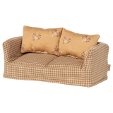 A vintage-style miniature sofa with a beige and brown checkered pattern. It features two floral-patterned cushions, conveying a cozy and nostalgic vibe.