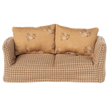 A vintage-style miniature sofa with a beige and brown checkered pattern. It features two floral-patterned cushions, conveying a cozy and nostalgic vibe.