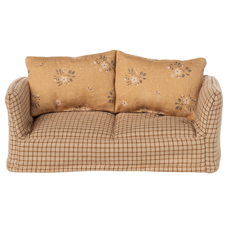 A vintage-style miniature sofa with a beige and brown checkered pattern. It features two floral-patterned cushions, conveying a cozy and nostalgic vibe.