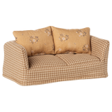 A vintage-style miniature sofa with a beige and brown checkered pattern. It features two floral-patterned cushions, conveying a cozy and nostalgic vibe.