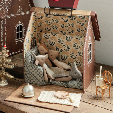 Maileg deer plush toys lounging on a couch inside a gingerbread dollhouse.