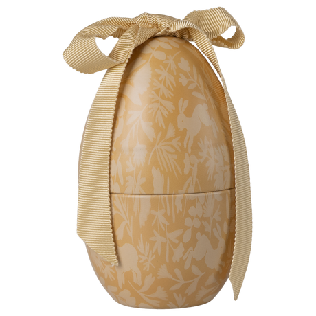 Golden egg-shaped container with white floral and rabbit patterns, tied with an elegant cream ribbon. The image conveys a festive and elegant tone.