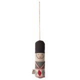 Cloth toy soldier ornament with a black hat, embroidered face, and patterned uniform hangs from a string against a white background.