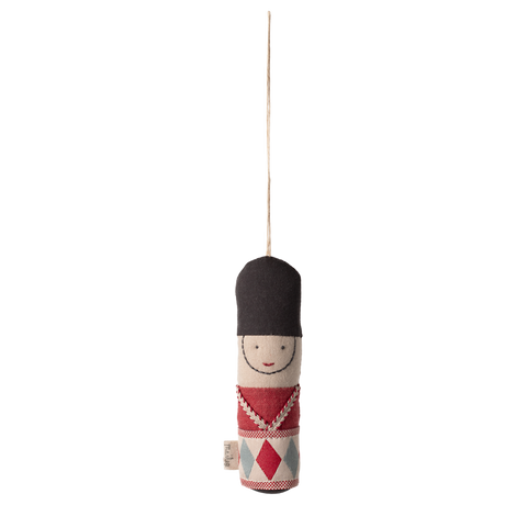 A hanging ornament depicting a smiling toy soldier with a tall black hat and red, blue, and white uniform, set against a white background.