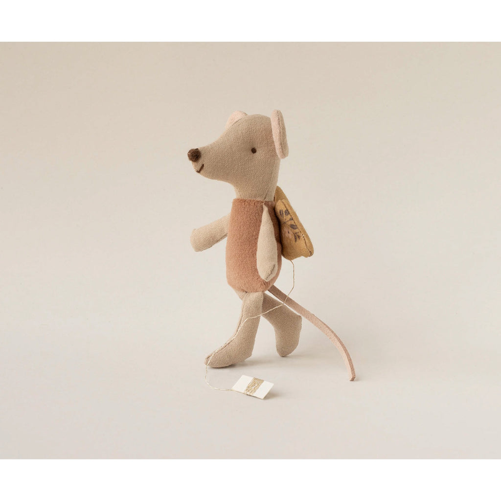 A soft, beige toy mouse with large ears and angelic wings, wearing a brown shirt. The mouse appears joyful, emanating a playful, whimsical vibe.