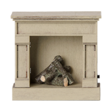Miniature off-white dollhouse fireplace with tiny logs inside on a white background.