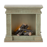 A decorative miniature fireplace with a greenish-gray finish, holding several stacked logs inside, showcasing a cozy and rustic vibe.
