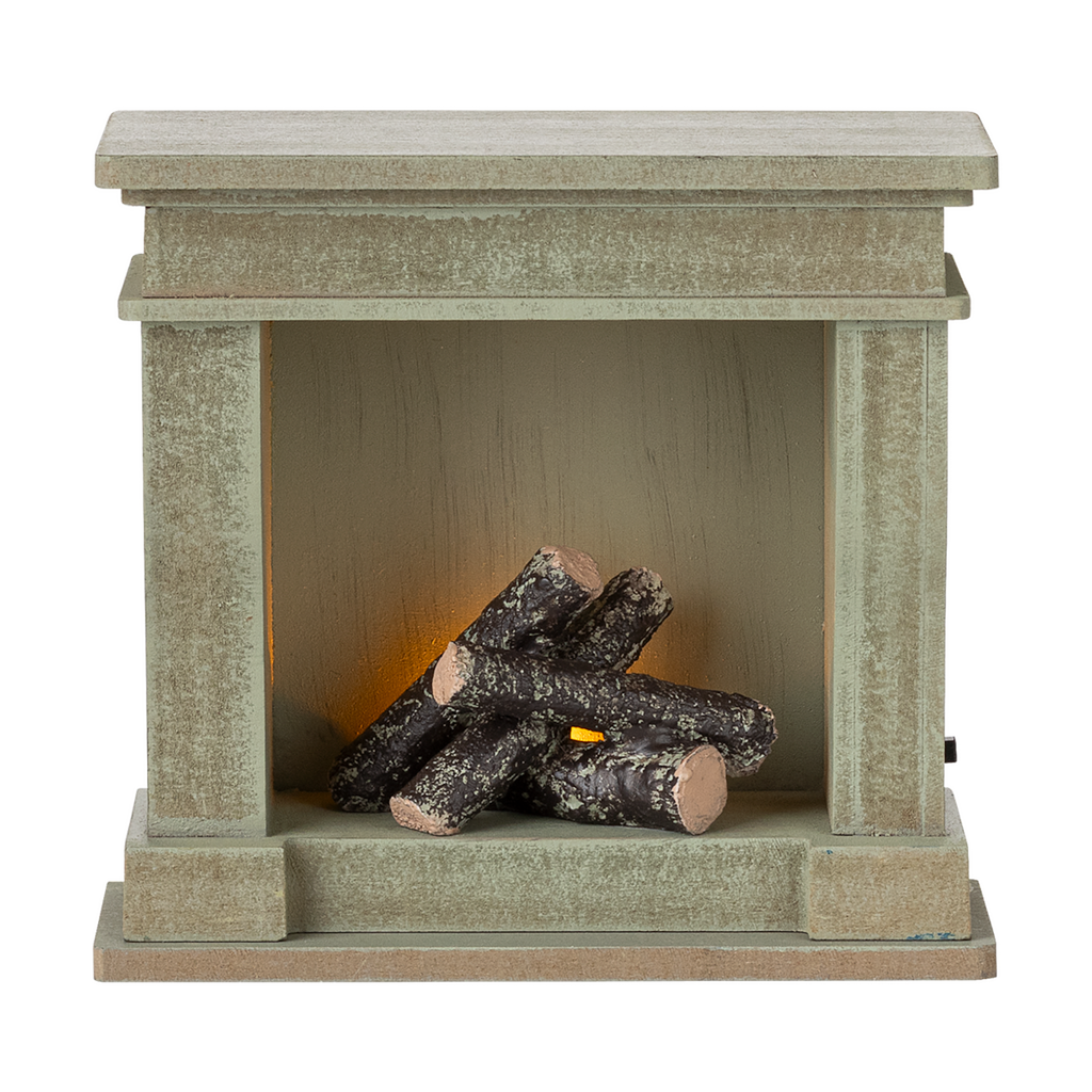 A decorative miniature fireplace with a greenish-gray finish, holding several stacked logs inside, showcasing a cozy and rustic vibe.