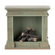 A decorative miniature fireplace with a greenish-gray finish, holding several stacked logs inside, showcasing a cozy and rustic vibe.